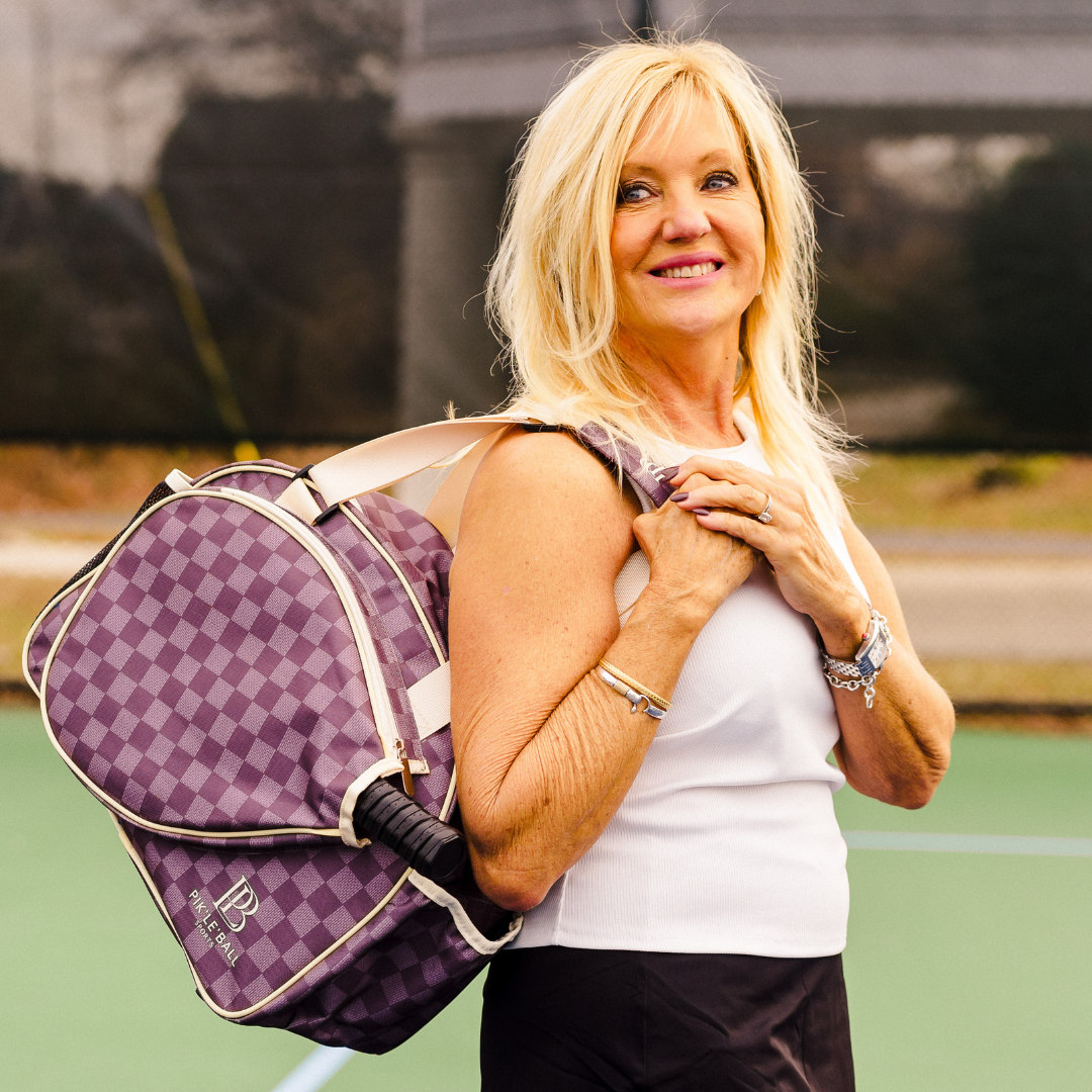 Woman carrying a fashionable pickleball bag with stylish brown checkered design.
