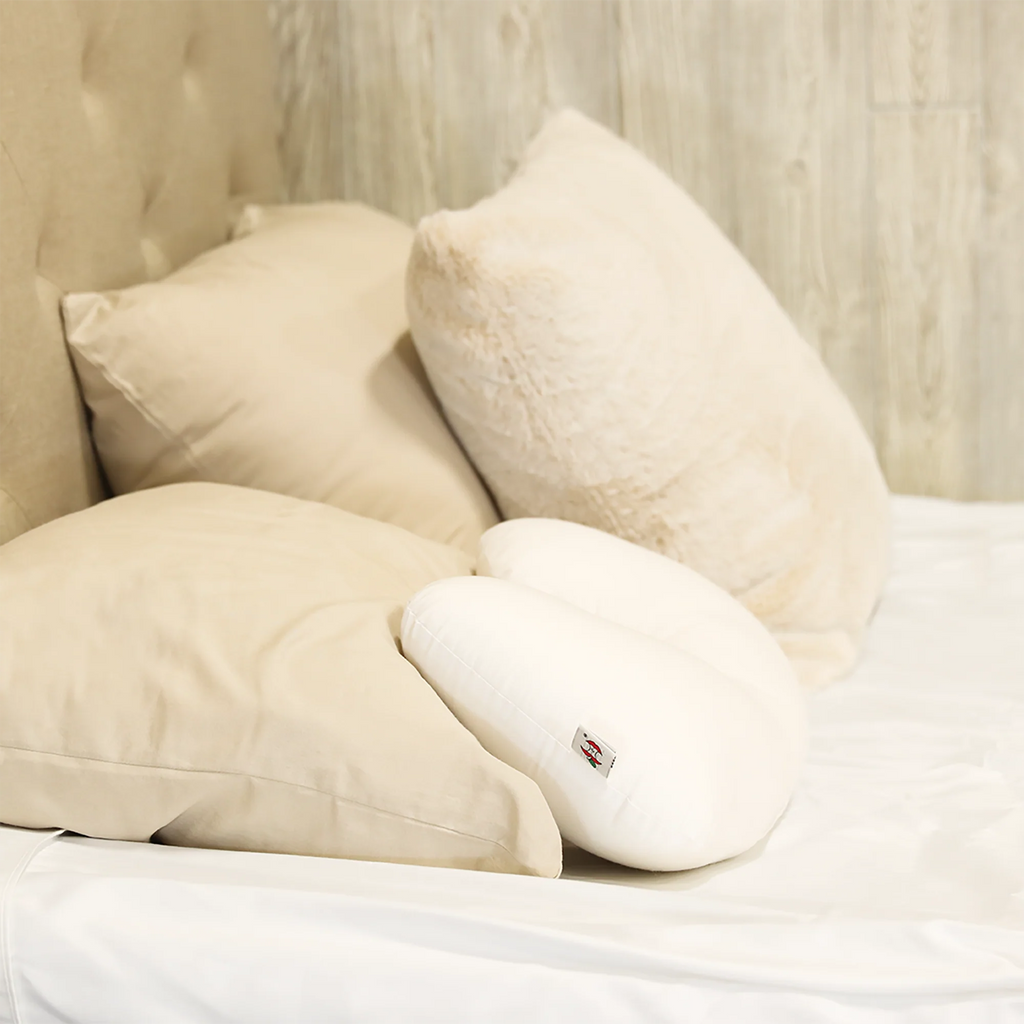 Beige pillows and white travel core pillow on a bed with a visible brand logo.