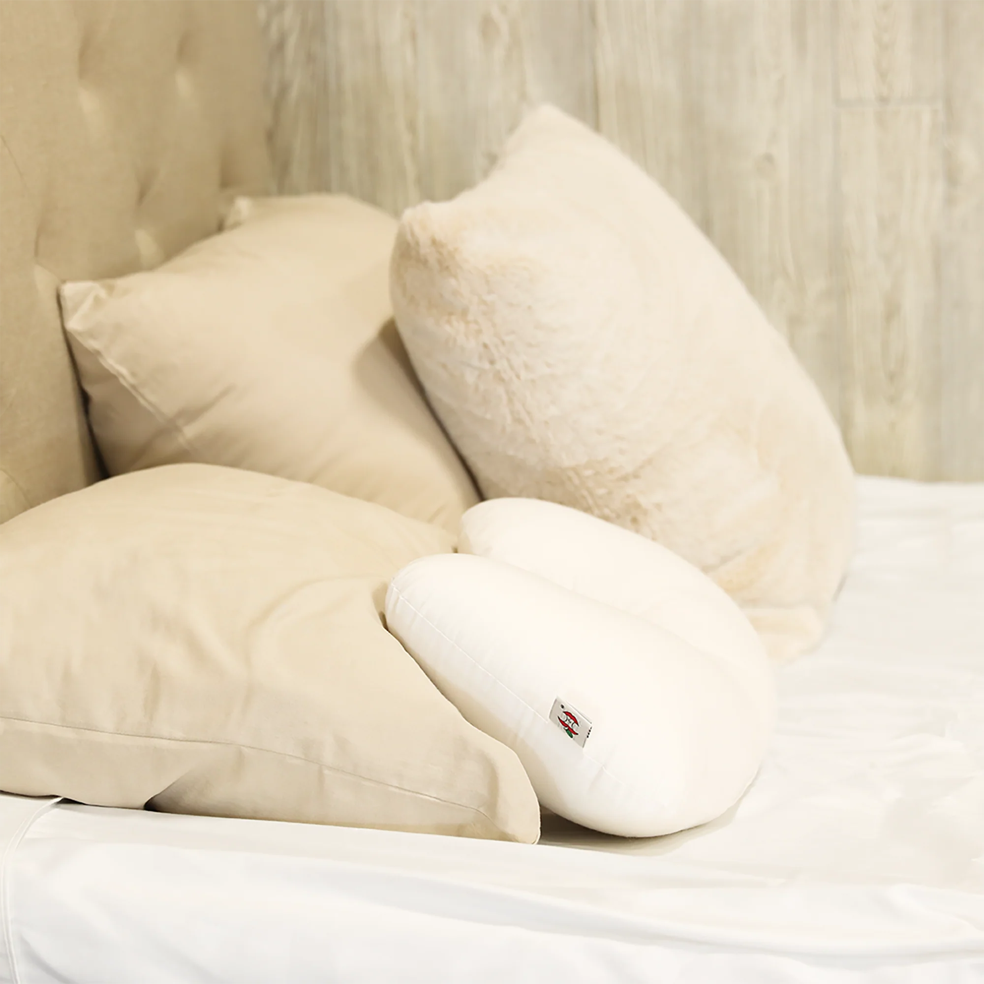 Beige pillows and white travel core pillow on a bed with a visible brand logo.
